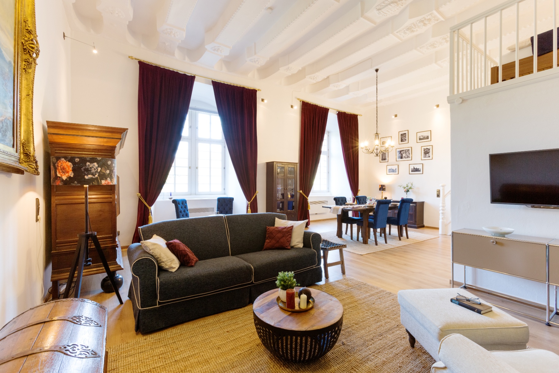Gemütliches Wohnzimmer mit Sofa, Burgunder-Vorhängen und Galerie